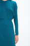 Close-up of a person wearing a Victoria Beckham Long Sleeve Dolman Midi Dress In Petroleum with seam detailing in luxurious cady fabric. Only the upper body and right arm are visible against a plain white background, exuding contemporary sophistication.