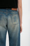 Close-up of a person wearing Victoria Beckham's Relaxed Straight Leg Jean In Antique Indigo Wash, focusing on the back pocket and brown belt against a white background.