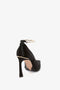 A single black Victoria Beckham Pointy Toe Pump in Black Satin with a gold ankle strap and a sleek 100mm heel, viewed from the back, against a plain white background.