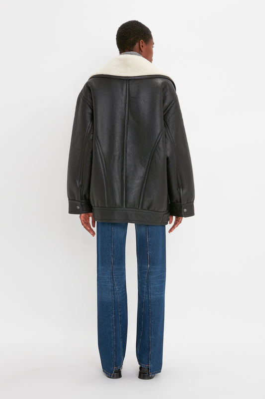 Individual facing away, donning an oversized silhouette of a Shearling Coat In Monochrome by Victoria Beckham and blue jeans.