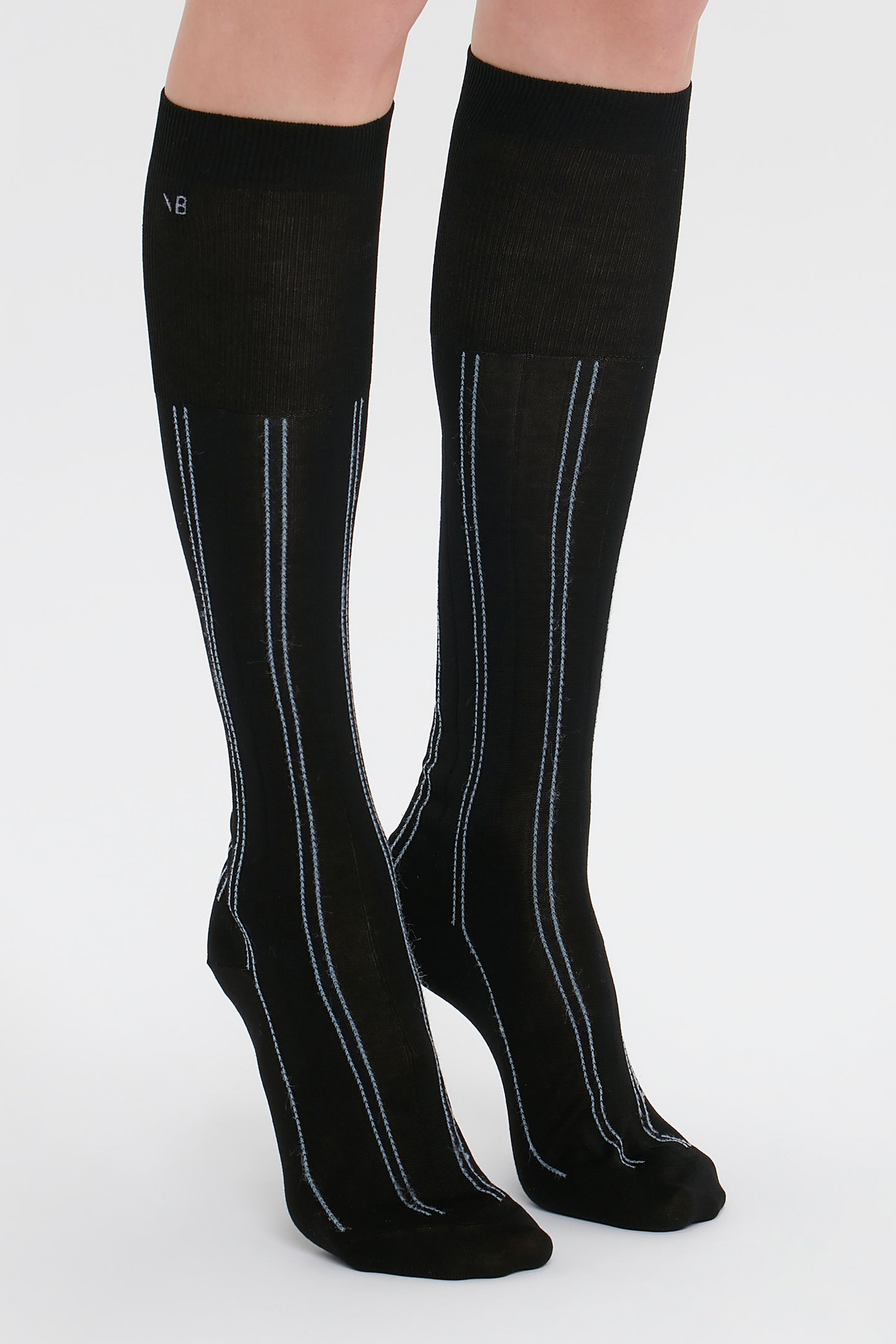 A pair of legs adorned with Victoria Beckham's Superfine Rib Socks In Black on a plain white background.