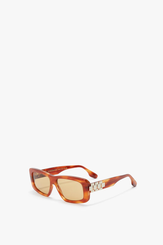 Chain Detail Rectangular Frame Sunglasses In Striped Blonde Havana by Victoria Beckham with light brown tinted lenses and gold geometric detailing on the temples feature a sophisticated rectangular frame.