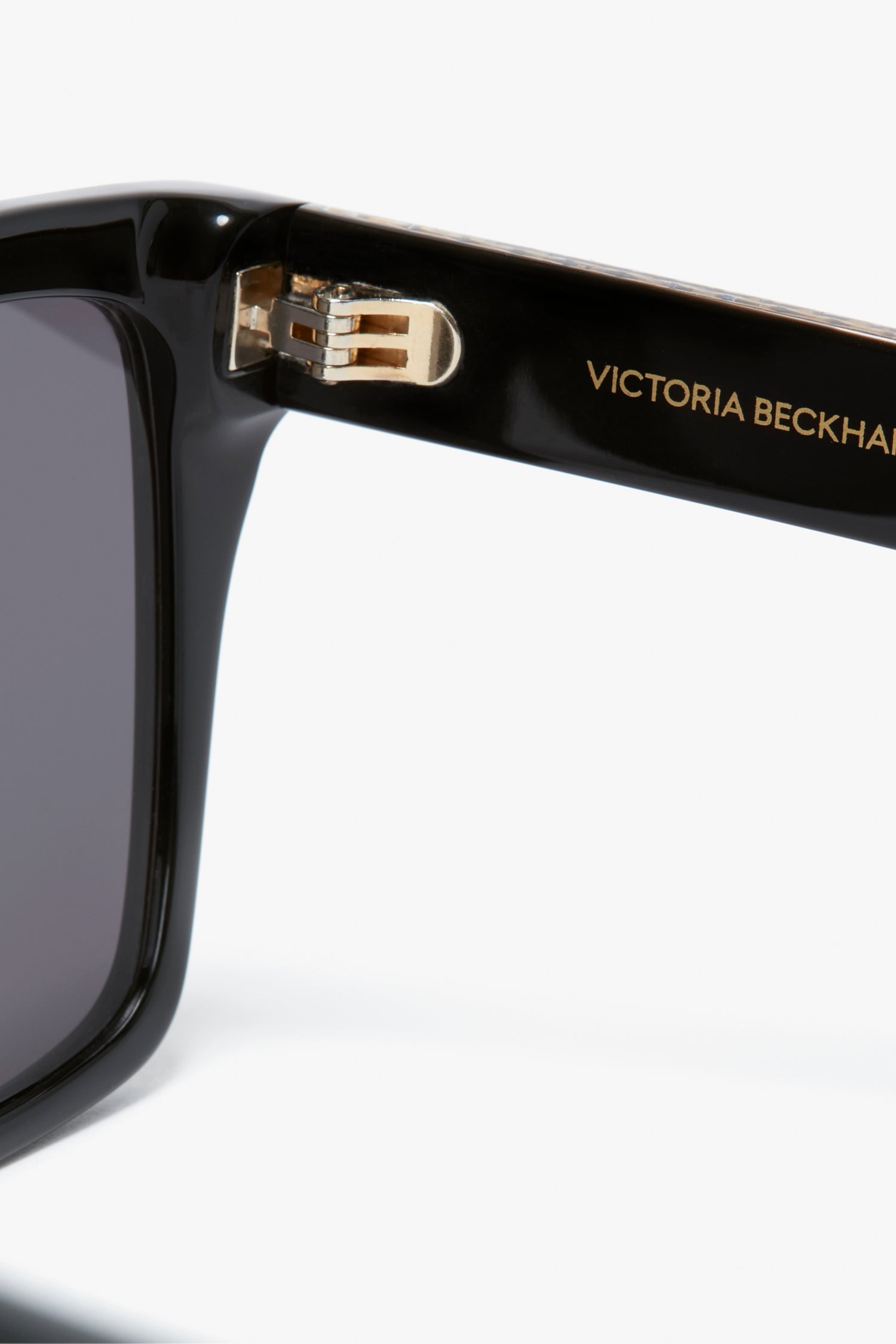 Close-up of the temple of black Victoria Beckham Layered Lens Visor Sunglasses In Black with "VICTORIA BECKHAM" inscribed in gold on the inside, part of the SS24 collection.