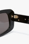 Close-up of Victoria Beckham Chain Detail Rectangular Frame Sunglasses In Black, focusing on the hinge and part of the lens.