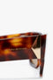 Close-up of a stylish pair of V Plaque Rectangular Frame Sunglasses In Tortoise featuring a brown tortoiseshell rectangular frame with gold detailing at the hinge. The name "Victoria Beckham" is inscribed on the temple, adding an elegant touch.