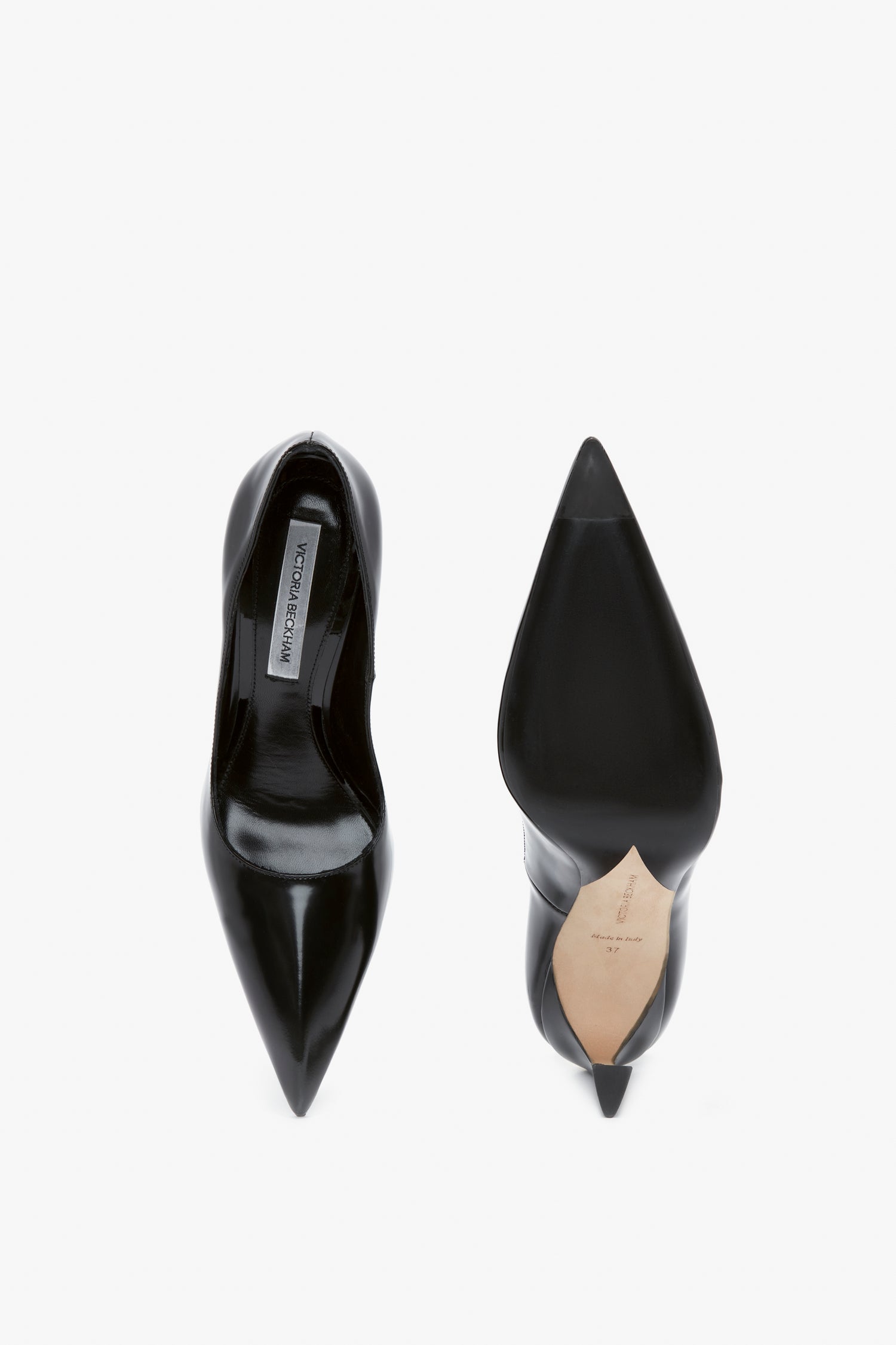 A pair of black, pointed-toe V Pump In Black Brushed Leather by Victoria Beckham. The shoe on the left is shown from the top view, highlighting its sleek design, while the one on the right is displayed from the bottom, showcasing its sculptural heel and detailed sole.