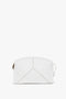 A white leather pouch with a zip closure and a minimalist, structured design, featuring subtle stitching patterns on the front has been replaced with the Exclusive Victoria Clutch Bag In White Leather by Victoria Beckham.