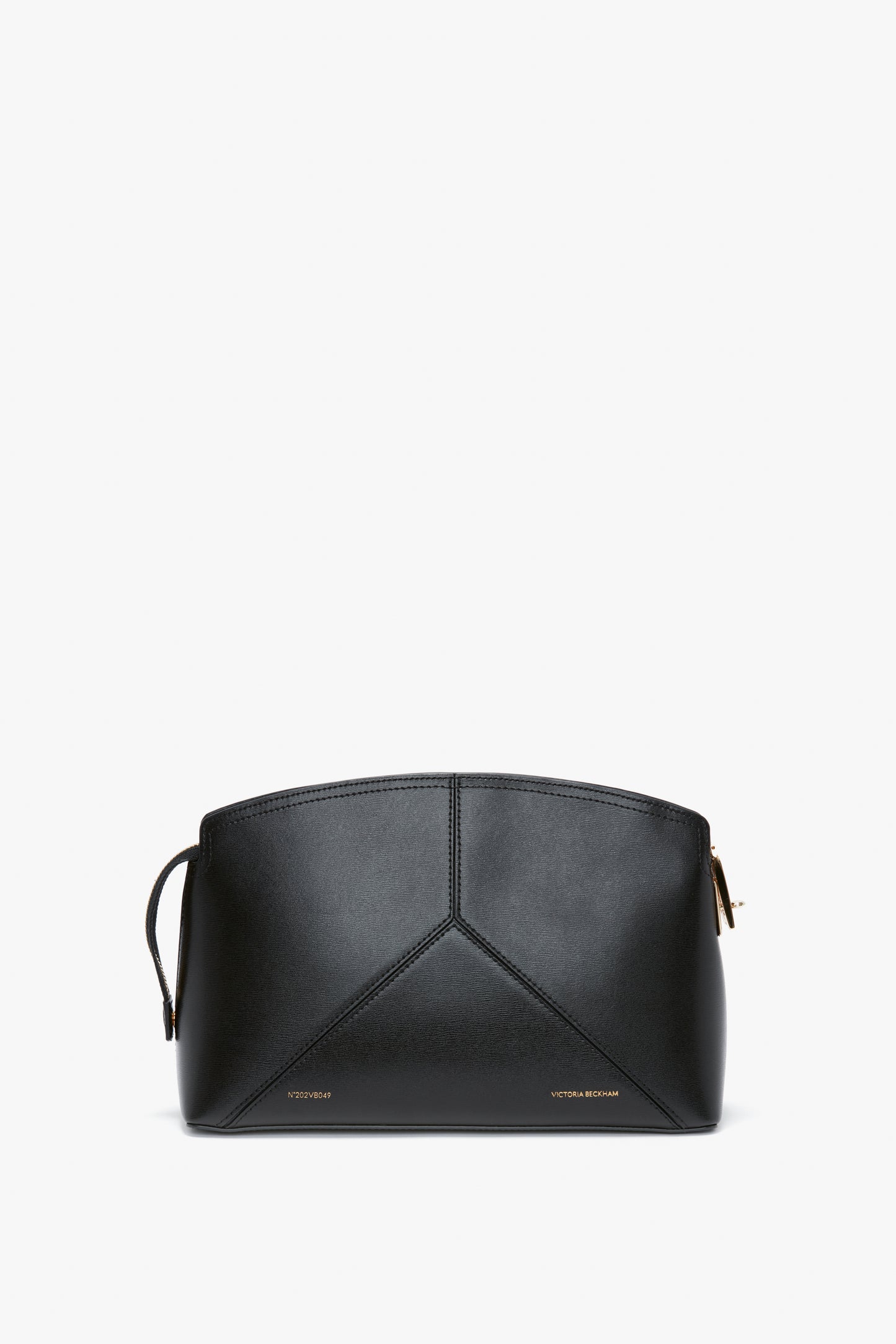 A Victoria Beckham Victoria Clutch Bag In Black Leather displayed against a white background. The bag features a minimalistic design with stitching details and a small gold logo at the bottom, showcasing a structured silhouette reminiscent of a Victoria Beckham leather clutch.