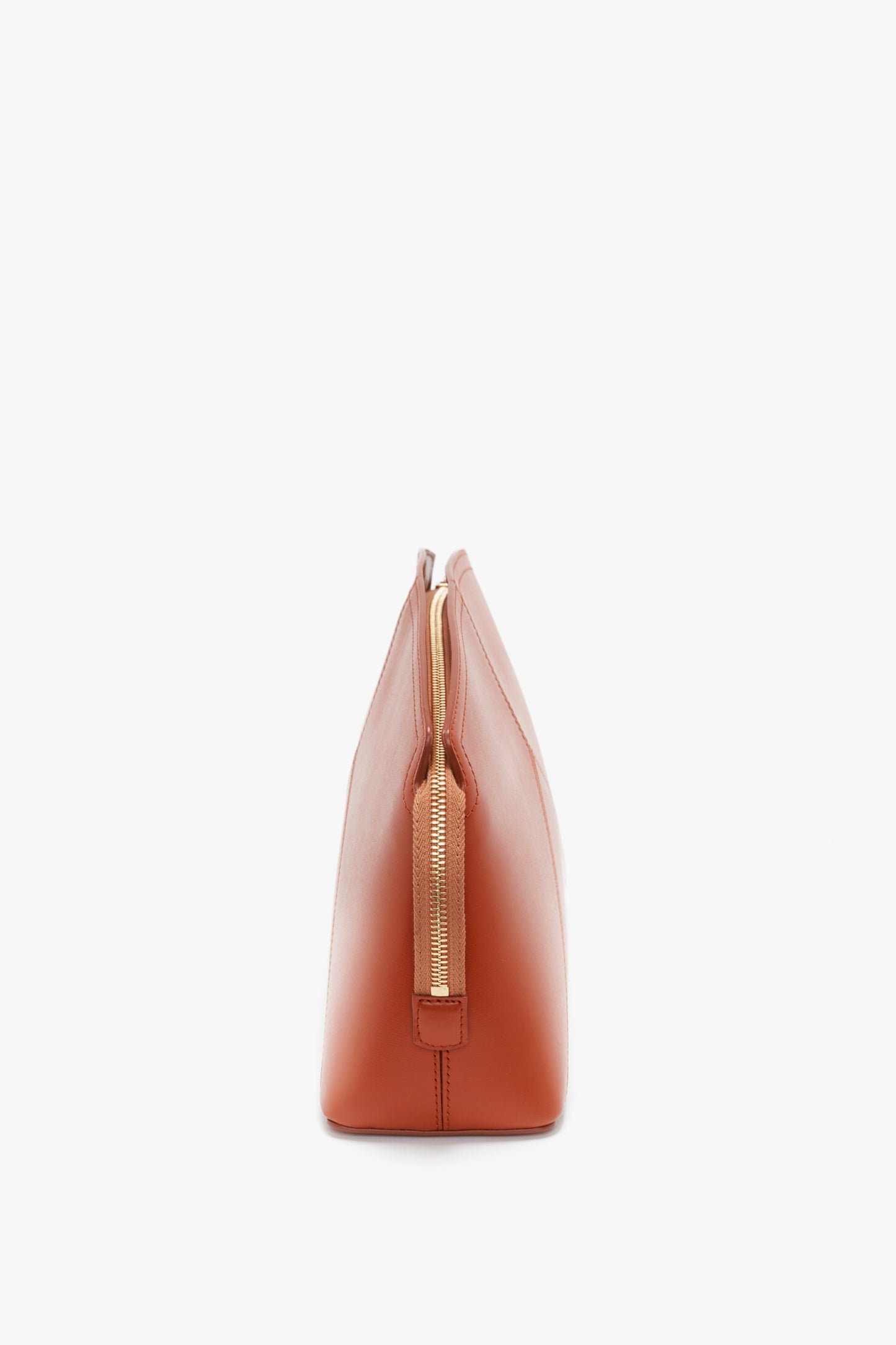 Side view of an orange-brown leather handbag with a gold zipper, reminiscent of a Victoria Beckham Victoria Clutch Bag In Tan Leather.