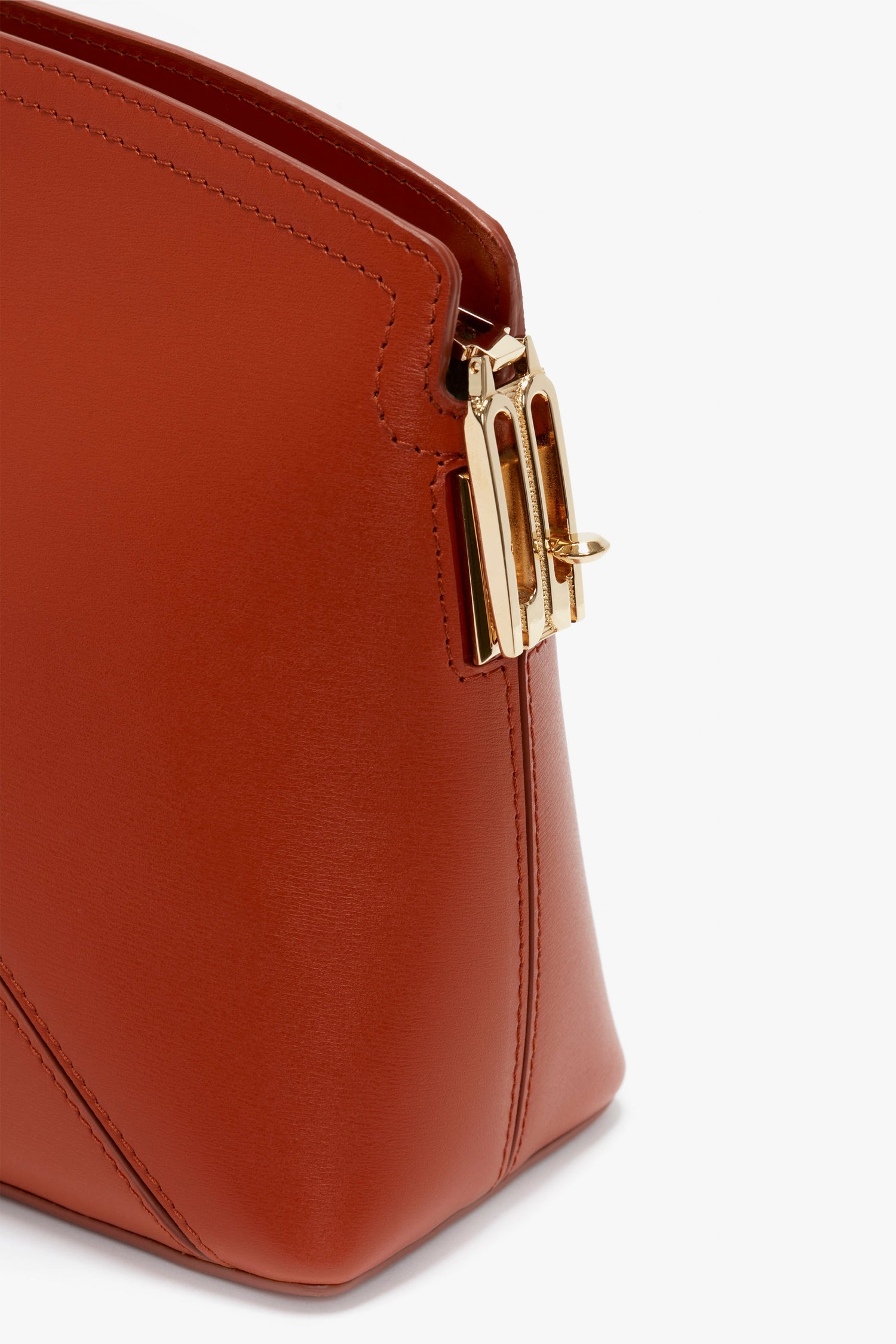 Close-up of a Victoria Beckham Victoria Clutch Bag In Tan Leather featuring a sleek gold clasp on a white background.