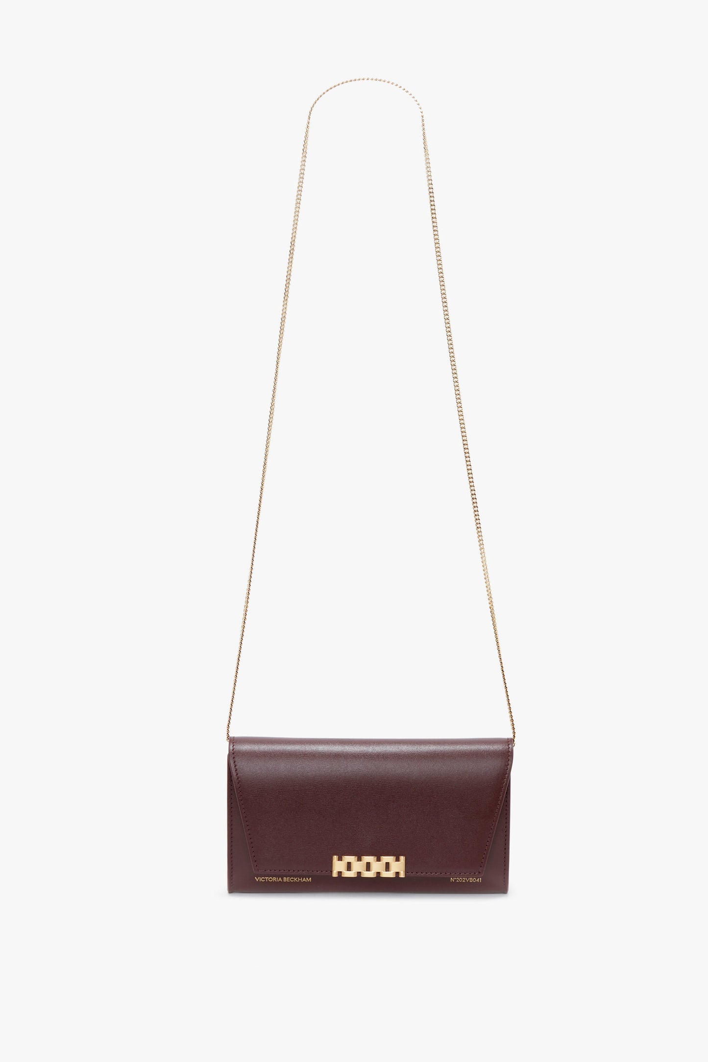 A small, rectangular Wallet On Chain In Burgundy Leather by Victoria Beckham with a gold chain strap and a gold geometric clasp, perfect for pairing with a gathered waist midi dress.