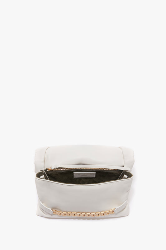 A Puffy Chain Pouch Bag With Strap In White Leather by Victoria Beckham with an open top showcasing a zippered interior compartment and gold hardware detailing on the front, complemented by a detachable shoulder strap.