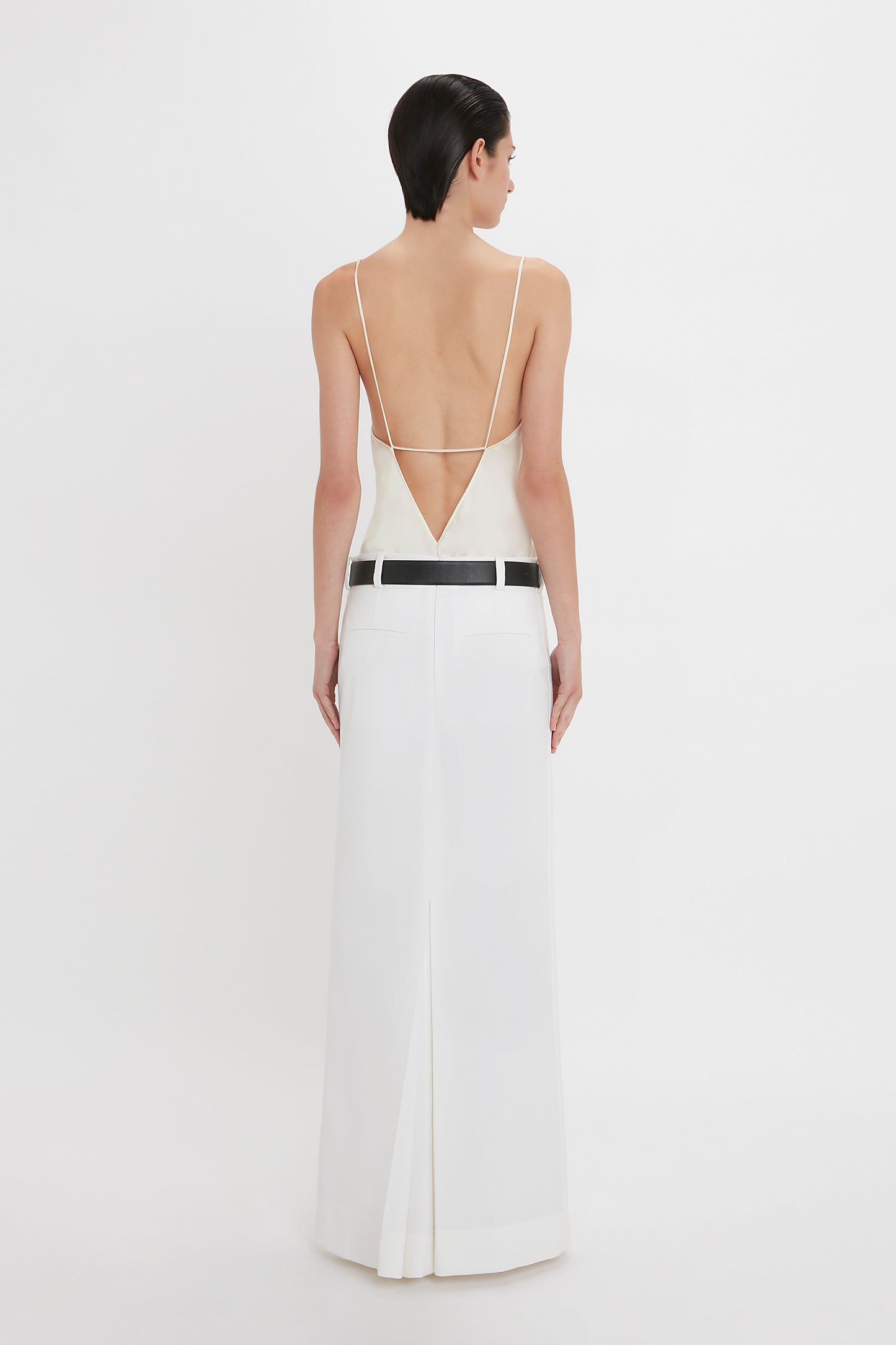 A person with short, dark hair wearing an Exclusive Tailored Floor-Length Pleated Skirt In Ivory by Victoria Beckham facing away from the camera.