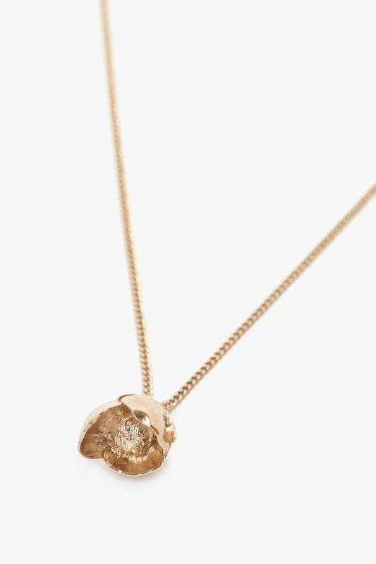 The Exclusive Camellia Flower Necklace In Gold by Victoria Beckham features a textured, organic-shaped pendant resembling a delicate flower bud. Expertly handcrafted from gold brushed brass, the design is minimalistic and elegant.