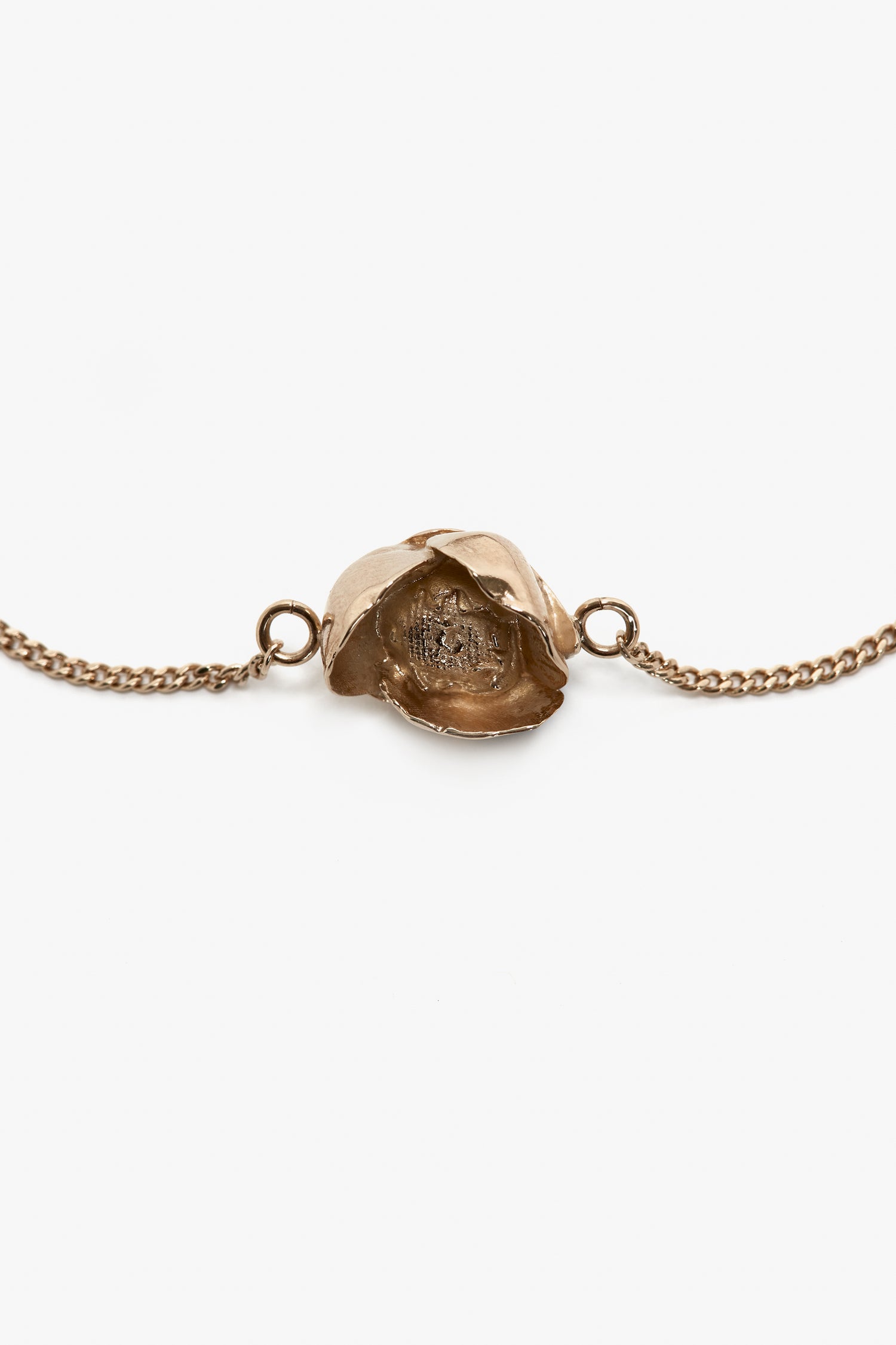 A gold-tone Victoria Beckham Exclusive Camellia Flower Bracelet In Gold featuring a detailed rosebud charm in the center, connected by an adjustable chain on both sides against a white background.