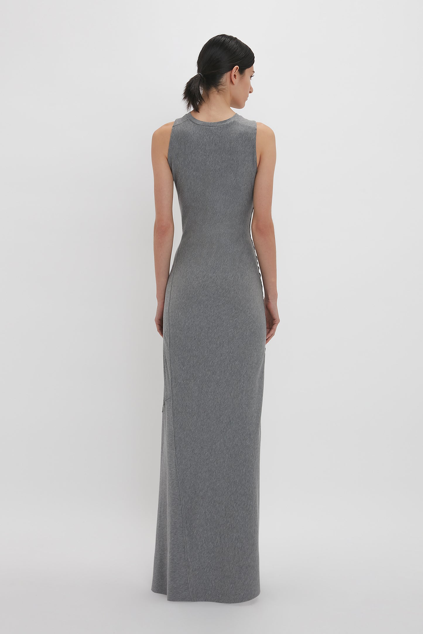 A person wearing a Victoria Beckham Frame Detailed Maxi Dress In Titanium made of melange jersey is facing away from the camera against a plain white background.