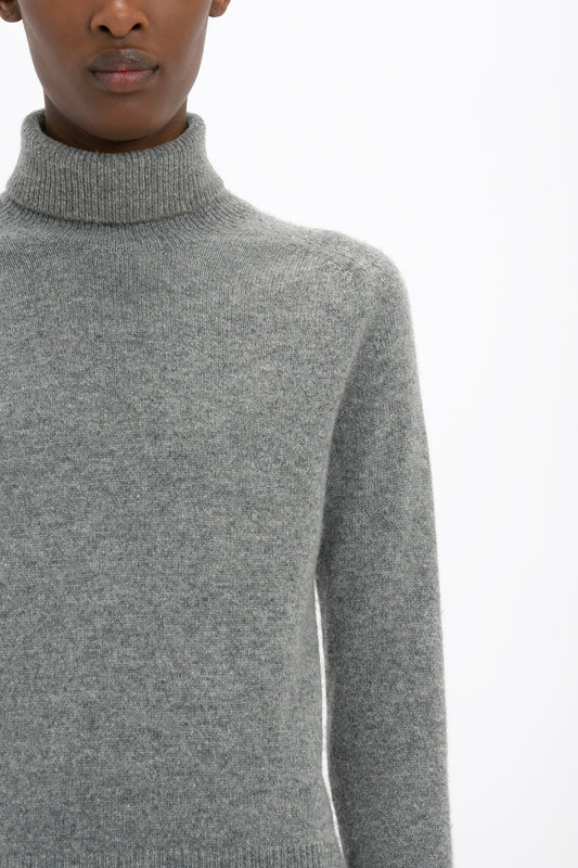 Person wearing a Polo Neck Jumper In Grey Melange by Victoria Beckham against a white background. Only the upper body and part of the face are visible. The versatile styling evokes a timeless elegance reminiscent of Victoria Beckham's monogram designs.