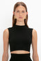 A woman with straight, light brown hair wearing a sleeveless black top and large, geometric gold earrings stands against a plain white background. The VB Body Scallop Trim Tank Top in Black by Victoria Beckham is the perfect summer essential for any wardrobe choice.