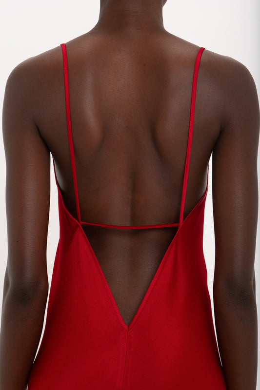 Person wearing a Victoria Beckham Low Back Cami Floor-Length Dress In Poppy Red, with thin straps and a backless design, viewed from the back.