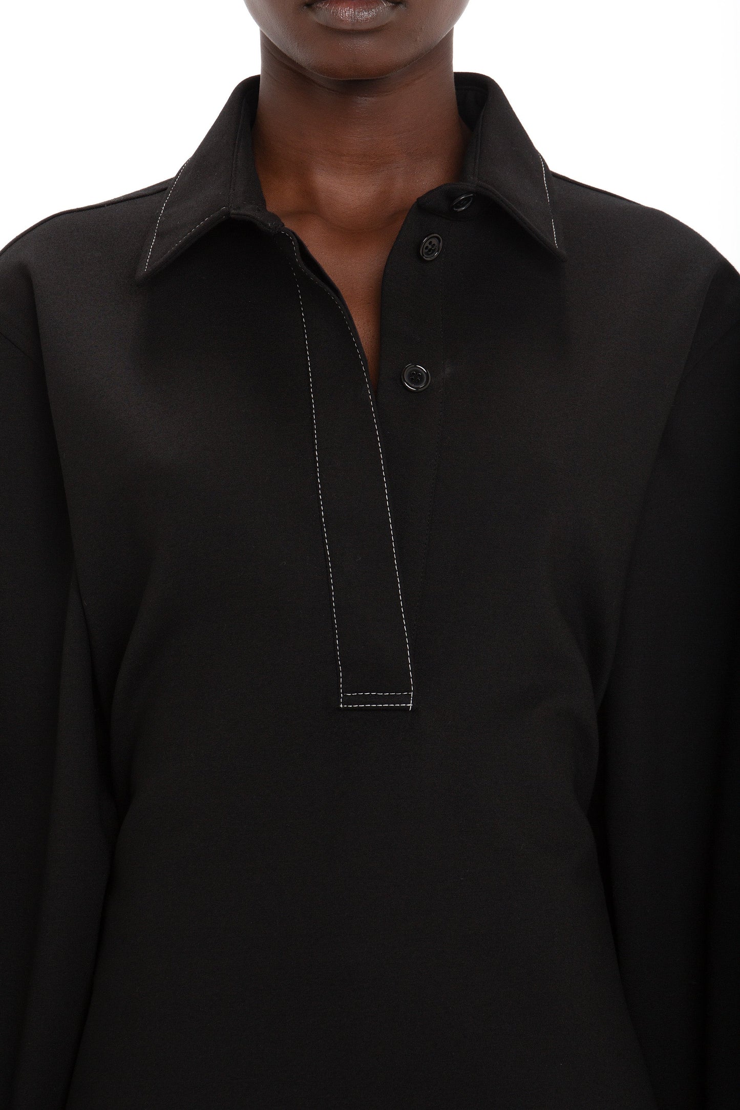 A person wearing a black long-sleeve Waistcoat Detail Ponti Top In Black by Victoria Beckham with a collar and buttoned neckline, adding a contemporary twist.