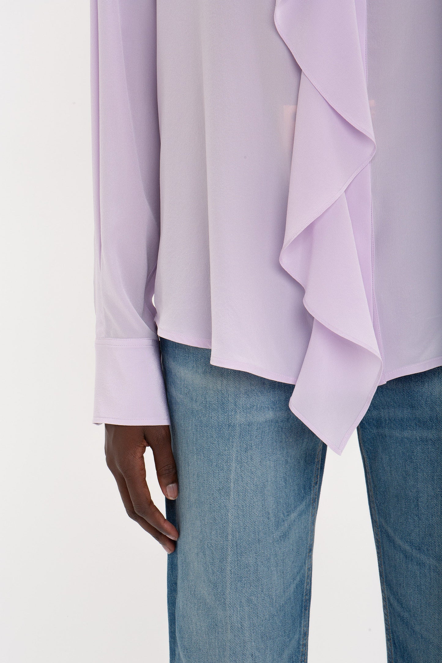 A person wearing a Victoria Beckham Asymmetric Ruffle Blouse in Petunia.