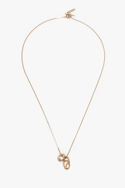 Victoria Beckham's Exclusive Abstract Charm Necklace in Light Gold featuring a thin chain and two intertwined circular pendants, crafted from 100% brass.