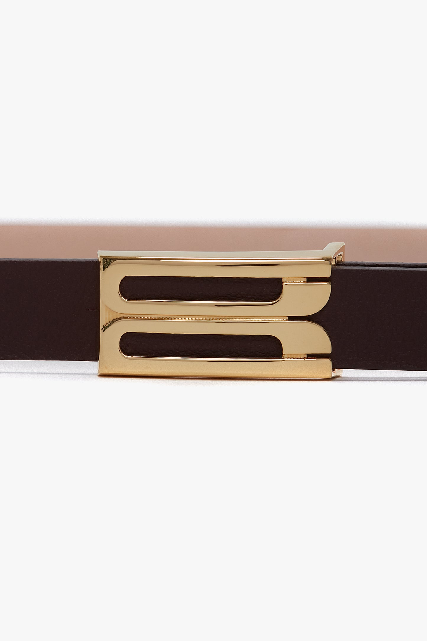 Close-up of a luxurious Burgundy leather belt with a gold rectangular buckle featuring two elongated cut-out slots. Crafted from smooth calf leather, the Exclusive Micro Frame Belt In Burgundy Leather by Victoria Beckham showcases elegance and sophistication.