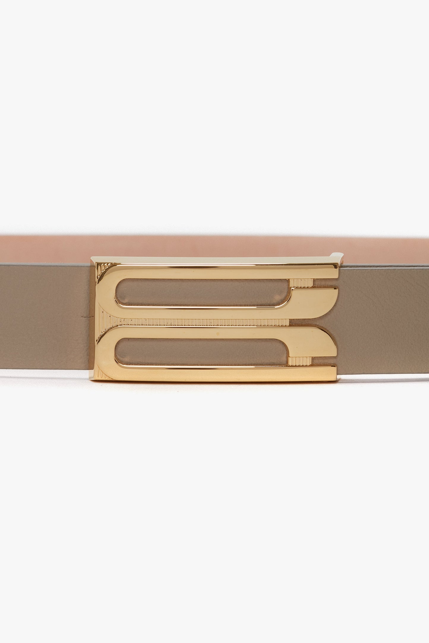 A fashion-forward beige belt with a gold rectangular frame buckle featuring two cutouts, the Exclusive Frame Belt In Beige Leather by Victoria Beckham.