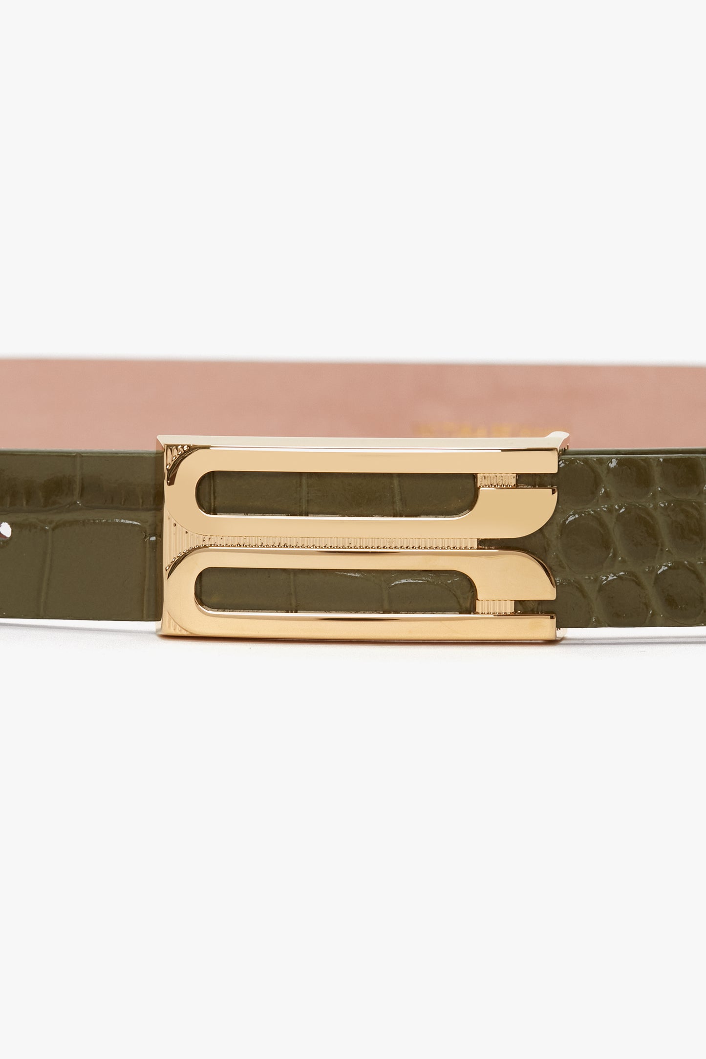 A close-up of the Victoria Beckham Exclusive Frame Belt In Khaki Croc Embossed Calf Leather featuring a gold double-prong buckle and a textured olive green strap with croc-embossed calf leather detailing.