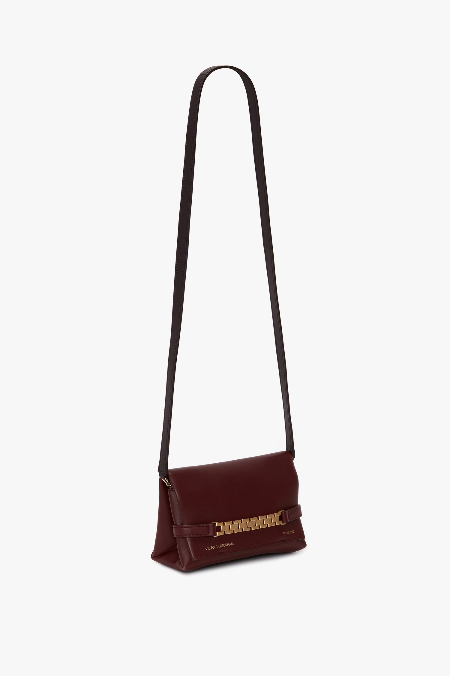 A Mini Chain With Long Strap Pouch Bag In Burgundy Leather by Victoria Beckham, featuring a gold chain detail on the flap.