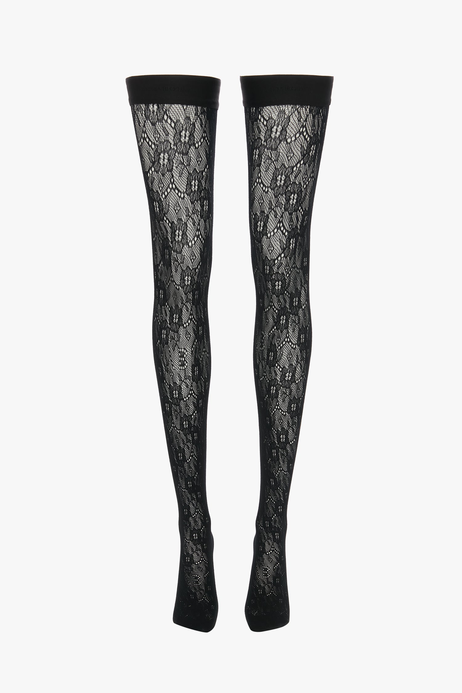 Two black Exclusive VB Monogram Lace Hold-Ups In Black by Victoria Beckham with a floral pattern and solid top bands against a plain white background showcase a sheer finish and seamless construction.