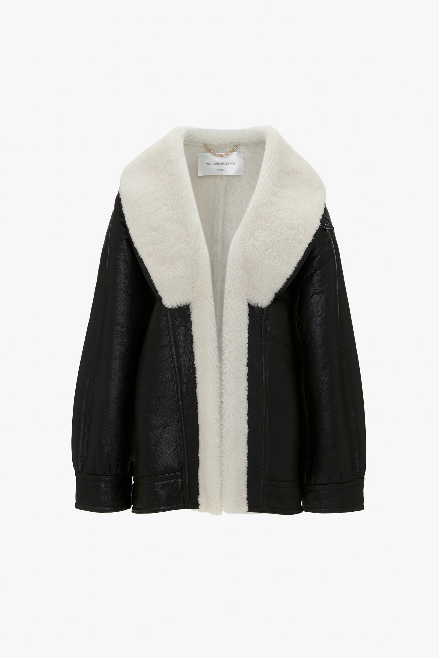 Shearling Coat In Monochrome by Victoria Beckham with a wide, cream black shearling collar and lining, shown against a plain white background. The design emphasizes an oversized silhouette, making it a statement shearling coat perfect for any stylish wardrobe.