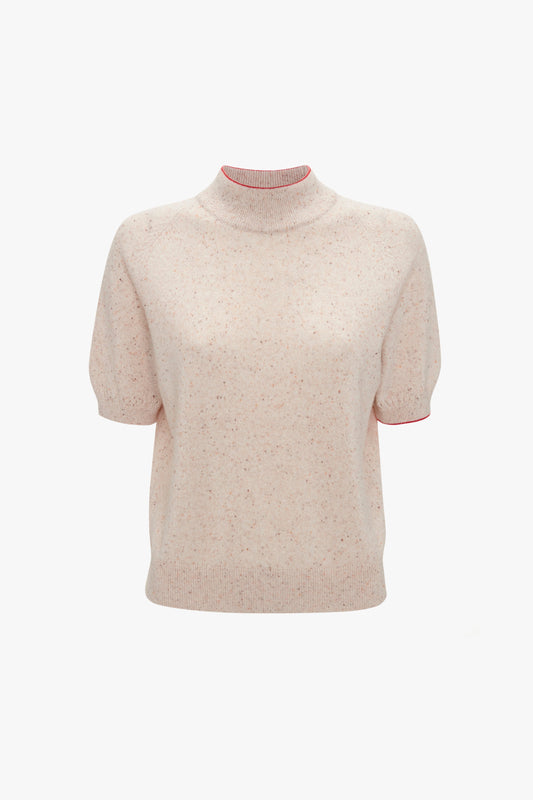 A short-sleeve, light pink sweater with a speckled pattern and a mock neck collar featuring pointelle lace stitch detailing. The collar has a contrasting red trim. This is the Short Sleeve Top In Nougat by Victoria Beckham.