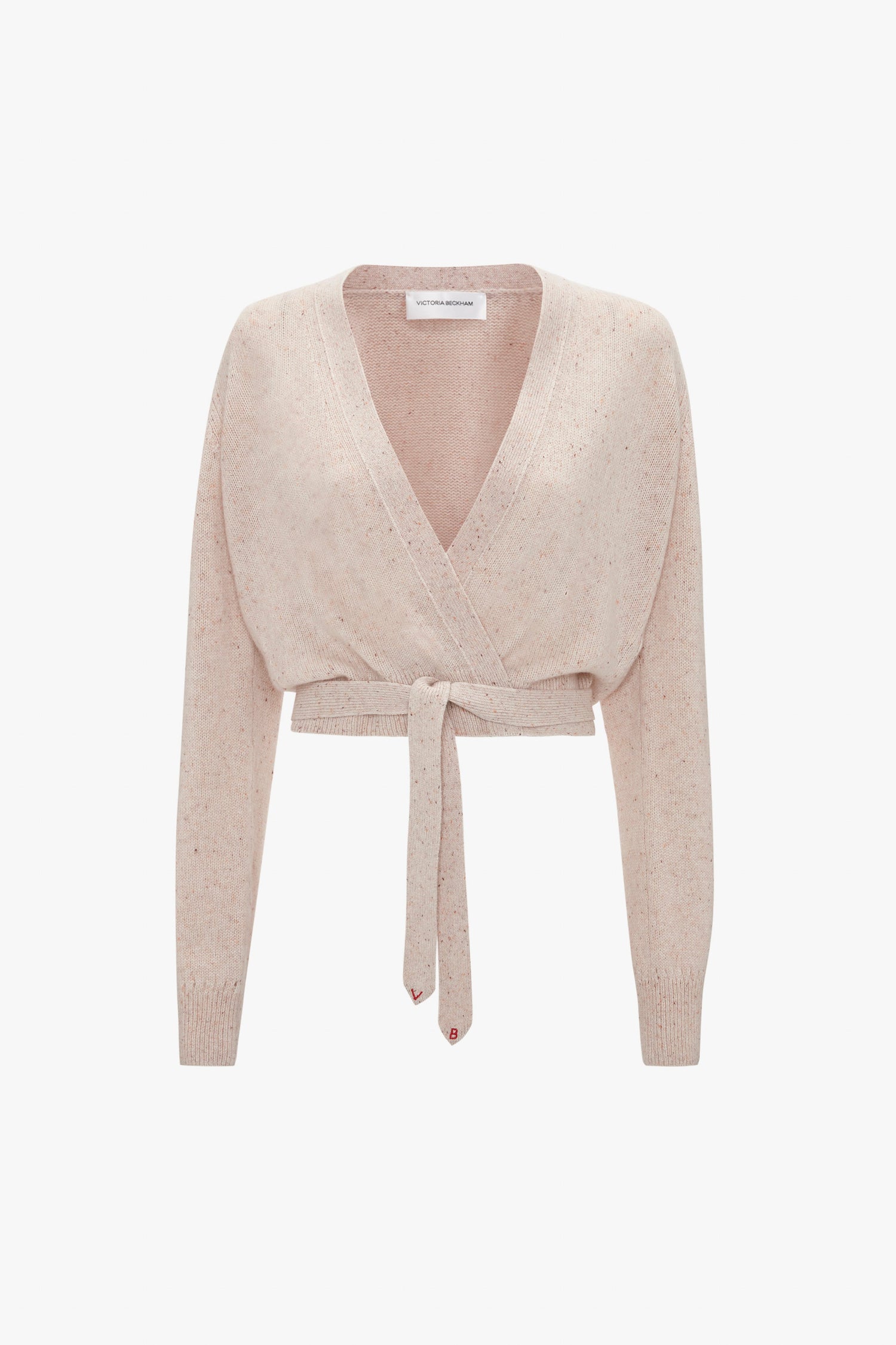 A light pink, long-sleeved Wrap Front Cardigan In Nougat with a V-neck design and a tie at the waist. This stylish piece, reminiscent of Victoria Beckham's elegant touch, is crafted from lightweight cashmere for ultimate comfort and luxury.