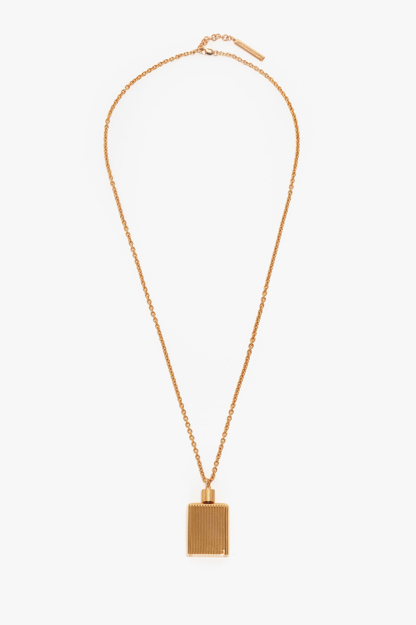 A Victoria Beckham Exclusive Perfume Bottle Necklace In Brushed Gold with a rectangular-shaped pendant featuring vertical lines, reminiscent of a perfume bottle pendant necklace, displayed on a white background.