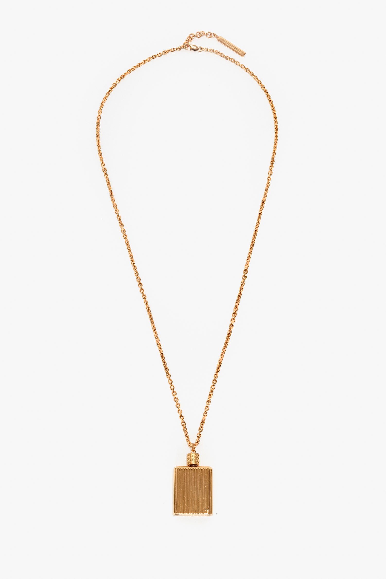 A Victoria Beckham Exclusive Perfume Bottle Necklace In Brushed Gold with a rectangular-shaped pendant featuring vertical lines, reminiscent of a perfume bottle pendant necklace, displayed on a white background.