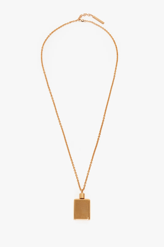 A Victoria Beckham Exclusive Perfume Bottle Necklace In Brushed Gold with a rectangular-shaped pendant featuring vertical lines, reminiscent of a perfume bottle pendant necklace, displayed on a white background.