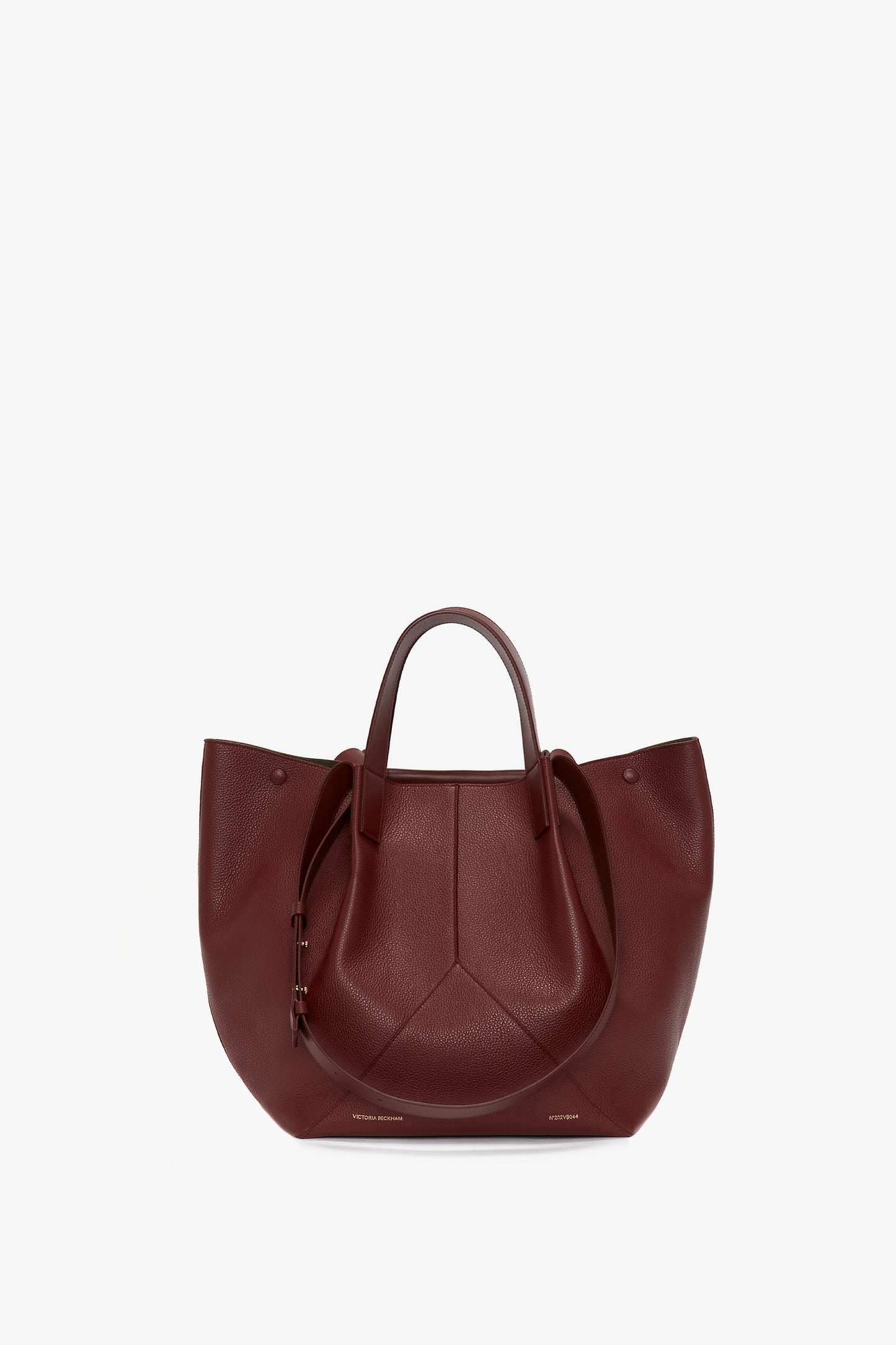 A large, dark red leather handbag crafted from grained leather with dual handles, an open top, and a structured shape featuring subtle stitch details. The **Victoria Beckham W11 Medium Tote Bag In Burgundy Leather** combines elegance and functionality perfectly.