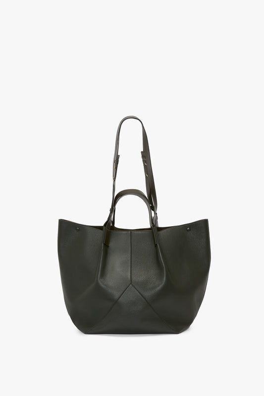 A W11 Jumbo Tote Bag In Loden Leather by Victoria Beckham in luxurious dark green grained leather with two sets of handles, one short for hand carrying and one long for shoulder carrying. The minimalist design features a slightly textured surface and adjustable straps for added versatility.