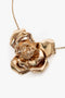 Close-up of a gold rose pendant on a thin gold chain necklace, displayed against a white background—this Victoria Beckham Exclusive Flower Necklace In Gold makes for an exquisite statement accessory.