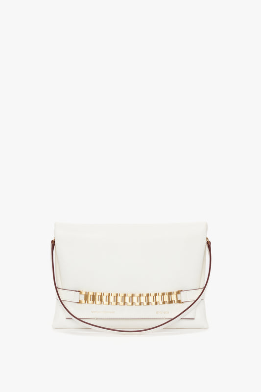 A white Nappa leather clutch handbag with a gold rectangular chain detail across the front and a thin brown strap on each side, embodying the elegance of a Chain Pouch Bag with Strap In White Leather by Victoria Beckham.